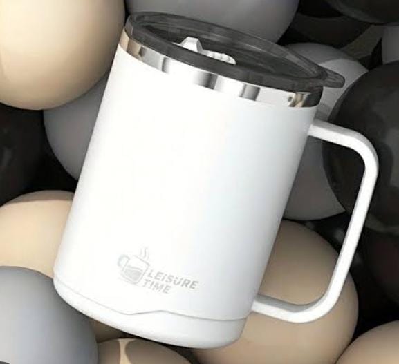 A white insulated travel mug with a handle, black lid, and silver rim, featuring the text 'LEISURE TIME' printed on the front, resting among smooth decorative stones.